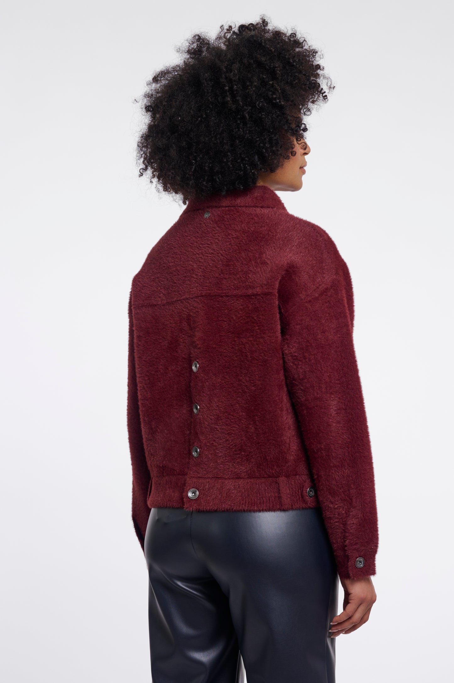 Person wearing a burgundy jacket on a white background